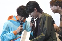 靴下の入った紙袋の中を覗き込む知念英和（左）、日野友輔（中央）、（右）