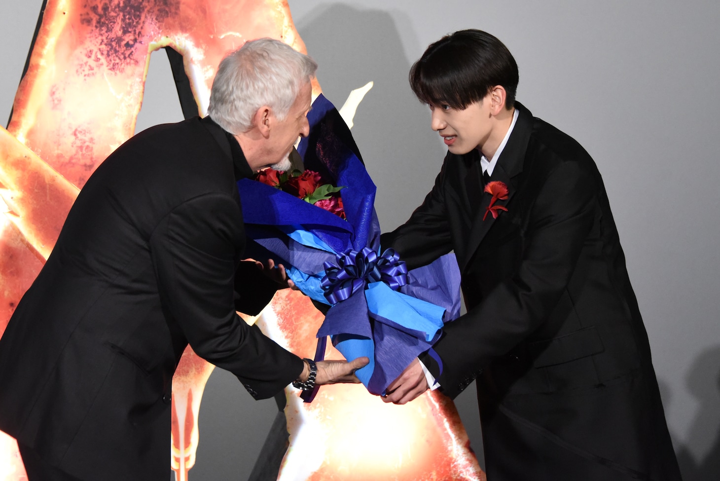 「アバター：ファイヤー・アンド・アッシュ」来日ジャパンプレミアより、宮世琉弥（右）から花束を受け取るジェームズ・キャメロン（左）