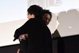 大友啓史（手前）とハグをする佐藤健（奥）
