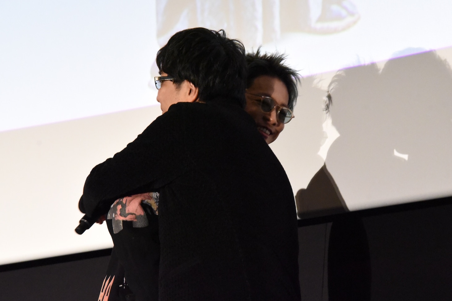 大友啓史（手前）とハグをする佐藤健（奥）