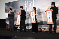 初めて舞台挨拶に登壇した北島岬（左）がうまく巻物を開けず、ほほえましそうに見守る登壇者たち