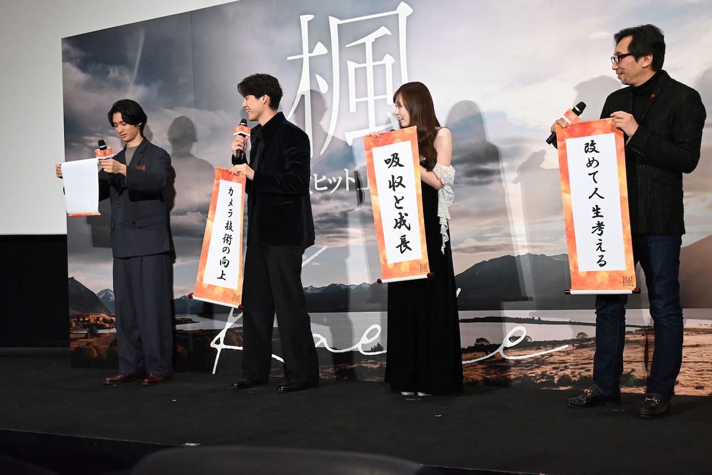 初めて舞台挨拶に登壇した北島岬（左）がうまく巻物を開けず、ほほえましそうに見守る登壇者たち