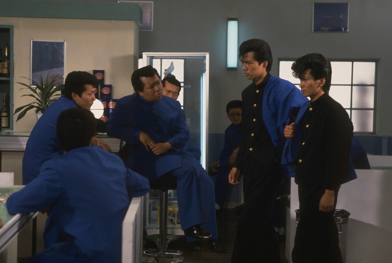 映画2作目「ビー・バップ・ハイスクール 高校与太郎哀歌」より。本作において、城東工業のナンバー2・テルが自分たちの力を誇示する手段としたのが、愛徳高校の生徒からボンタンを剥ぎ取る「ボンタン狩り」。ヒロシとトオルも一度は狩られてしまう ©︎東映