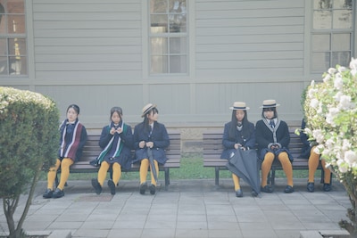 映画「白の花実」場面写真。カラータイツが目を引くコーディネート