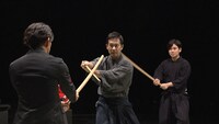 「明鏡止水 武のKAMIWAZA」第4回「驚異の回転！スノーボード・ハーフパイプ」より、岡田准一（左）と木刀を交える是風会・髙無宝良（中央）