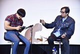 カリンバで「楓」を演奏する青木マッチョ（左）。その様子をスマホで撮影する行定勲（右）