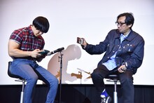 カリンバで「楓」を演奏する青木マッチョ（左）。その様子をスマホで撮影する行定勲（右）