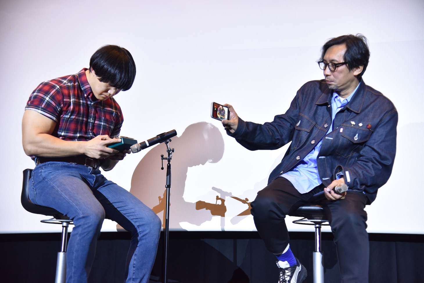 カリンバで「楓」を演奏する青木マッチョ（左）。その様子をスマホで撮影する行定勲（右）