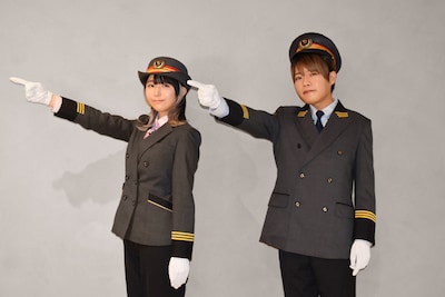 小田急電鉄の駅長の制服に身を包んだ羊宮妃那（左）と堀江瞬（右）