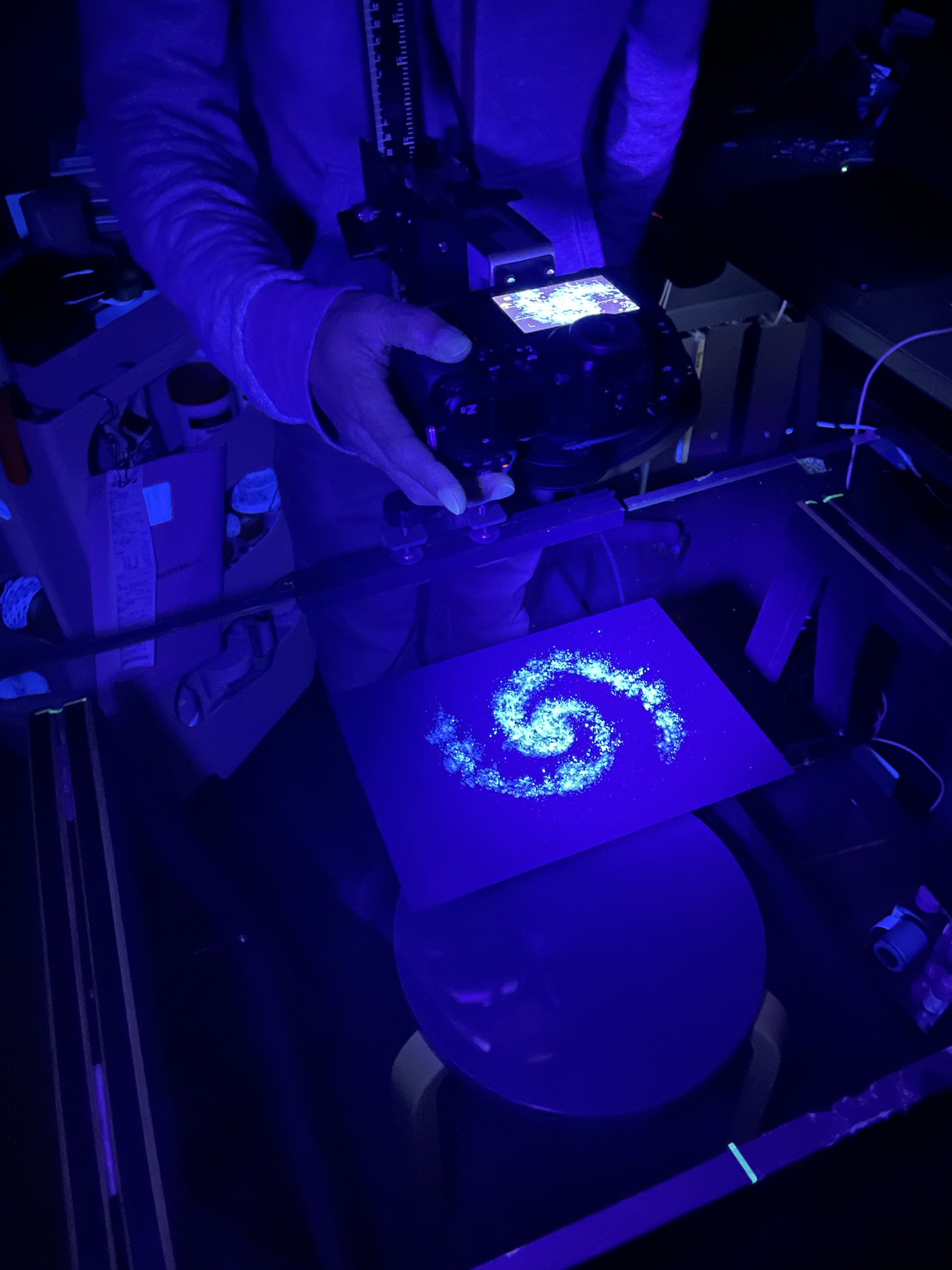 粉状のパステルを黒い紙に塗ったものをブラックライトで照らして宇宙の光を表現した