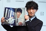 「津田健次郎PHOTOBOOK since1995」発売記念会見の様子。お気に入りのカット（右ページ）を見せる津田健次郎