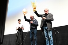 映画「そして彼女たちは」公開記念舞台挨拶の様子。河合優実から贈られた花束を高々と掲げるダルデンヌ兄弟