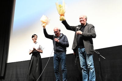 映画「そして彼女たちは」公開記念舞台挨拶の様子。河合優実から贈られた花束を高々と掲げるダルデンヌ兄弟