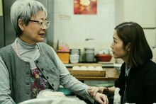 香港映画「旅立ちのラストダンス」場面写真より、エレイン・ジン（金燕玲）演じる食堂の店主・リン（左）、ミシェル・ワイ（衛詩雅）演じるマンユッ（右）