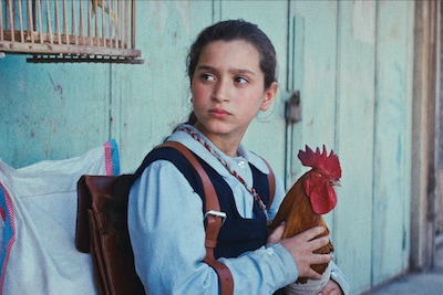 「大統領のケーキ」場面写真。バニーン・アハマド・ナーイフ演じる主人公のラミア。“友達”の雄鶏ヒンディを抱えている