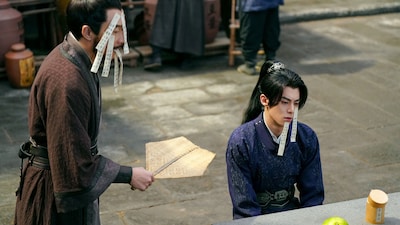 「大奉打更人―正義の銅鑼と王朝の闇―」新場面写真より、顔に詩札を貼られた楊凌 / 許七安（右）。本作では“クールかつパーフェクトな貴公子”というイメージにとどまらないワン・ホーディー（王鶴棣）の魅力を楽しめる