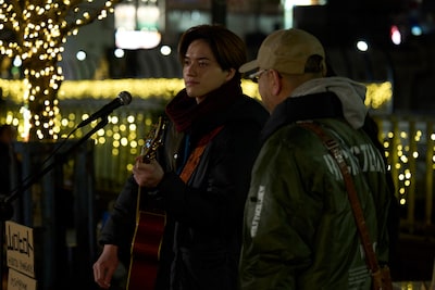 映画「正直不動産」メイキング写真。岩﨑大昇（KEY TO LIT）演じる山口ヒロトが、路上ライブで「優しい世界」を歌唱するシーン