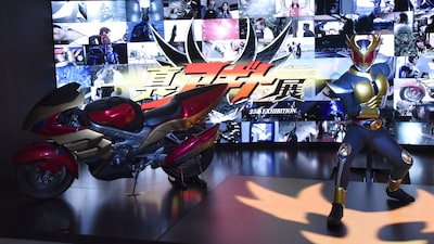 仮面ライダーアギト25周年記念「真アギト展」の様子。仮面ライダーアギト グランドフォームの立像（右）とマシントルネイダー（左）