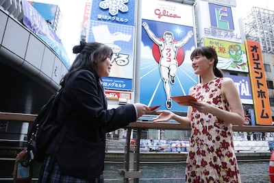 「人はなぜラブレターを書くのか」大阪・道頓堀のグリコサイン前でのプロモーションの様子。ラブレターを手渡しする綾瀬はるか（右）