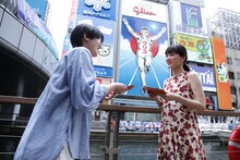 「人はなぜラブレターを書くのか」大阪・道頓堀のグリコサイン前でのプロモーションの様子。ラブレターを手渡しする綾瀬はるか（右）