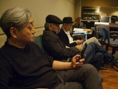 携帯電話をいじる3人（手前からイエロー・マジック・オーケストラの細野晴臣、坂本龍一、高橋幸宏）。