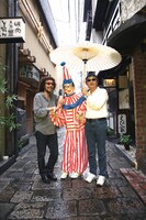 ひとつの傘に肩を寄せ合い、雨をしのぐ有山、太郎、上田。