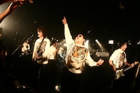 満員の渋谷La.mamaでトラ顔トレーナーを着込み、ダイノジとともにパフォーマンスを行う9mm Parabellum Bullet。