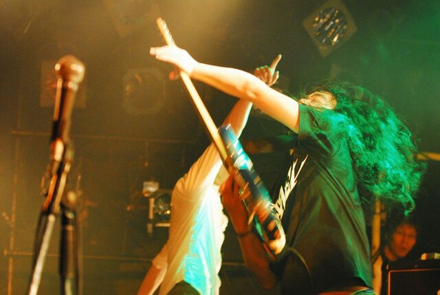 手前でギターを弾いているのがAxSxE。奥で天井を指さしているのが蔦谷。