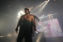 「ガリガリ君」を歌うピエール瀧。白バイ風ヘルメット、サングラス、子泣きじじいを思わせる蓑、青緑色のヒョウ柄スパッツという形容しがたい衣装で熱唱。（写真：北岡一浩）