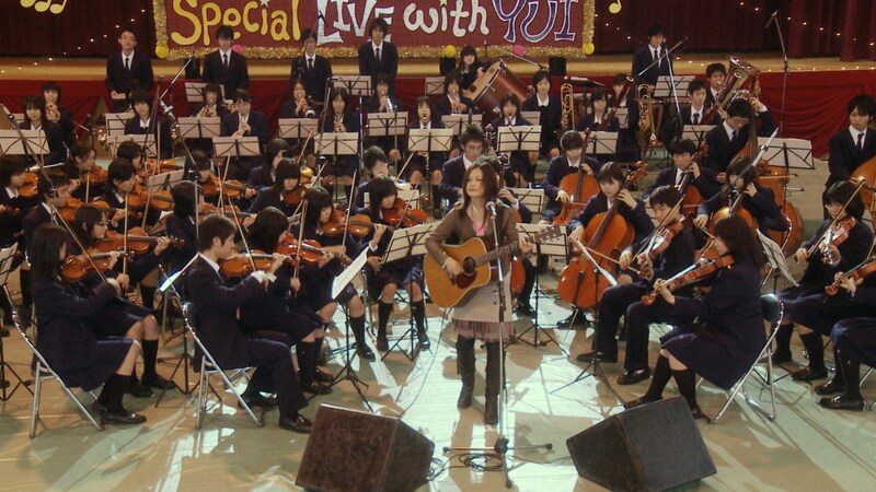 CMに出演したYUIと管弦楽部の生徒たち。