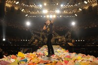 大量の紙飛行機に囲まれるフミヤさん。