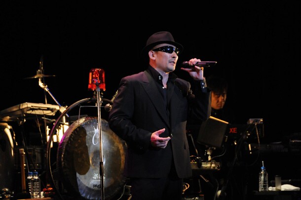 憧れのピンキラとの共演に沸き上がる喜びを、黒いサングラスの奥に隠した横山剣。後ろは銅鑼（photo：堀清英）。