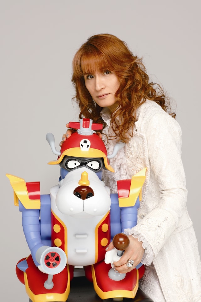 コミカルなヤッターワンのフィギュアを抱えながらも、耽美でロマンチックな雰囲気が隠し切れない高見沢俊彦。