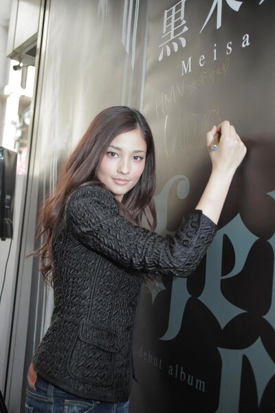 笑顔でタペストリーにサインを入れるメイサ。