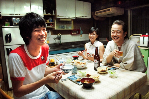映画のワンシーン。夕食の席で談笑する純（渡辺大知）と父（リリー・フランキー）、母（堀ちえみ）。
