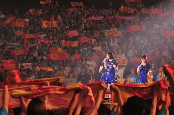 購入したオフィシャルグッズのタオルを頭上に掲げ3人に見せるオーディエンスたち。