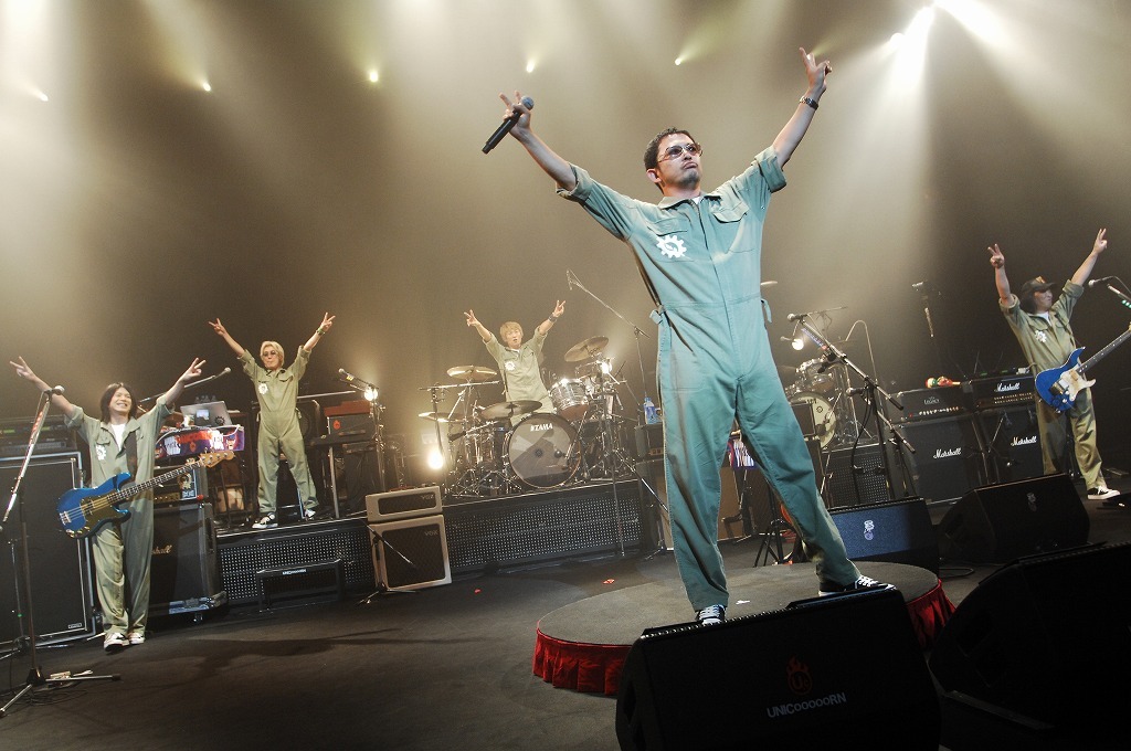 メンバー全員が両手を上げピース。毎公演の3曲目演奏直後に、このポーズを取っていた（写真は沖縄公演の様子）。