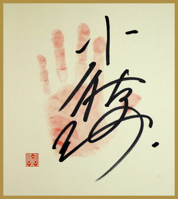 写真は小錦の偽サイン「Konishiki / UKAWA NAOHIRO 2007」（270X240 / 紙にペン Courtecy of YAMAMOTOGENDAI）。大胆な筆の運びと小振りな手形が印象的。