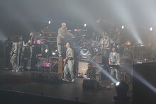 お揃いのつなぎを着込んで演奏するユニコーンの5人。この日の衣装は、ツアー中に一番多く着用したアーミーグリーンのつなぎ。背中にはメンバーを表すアルファベット1文字が入っている。ちなみに武道館3DAYSの初日となった5月19日には赤のつなぎ、2日目の5月20日にはジャケットとネクタイの学生コスプレで登場した。