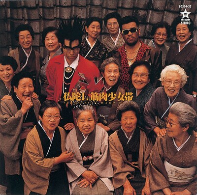 写真は1988年にリリースされたメジャー1stアルバム「仏陀L」ジャケット。大槻ケンヂと三柴江戸蔵（三柴理）の周りを囲む15人のお婆さんは、筋肉少女帯のメンバーではない。