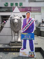 眠らない街、新宿。百獣の王ライオンを前に堂々胸を張る坂上弘の等身大パネル。