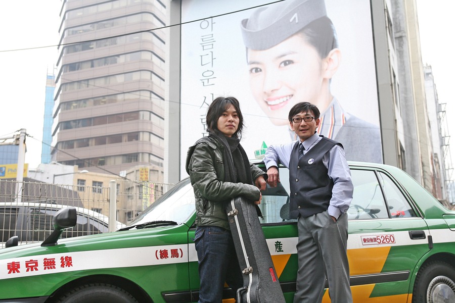 ギターケースを抱えているのが山田将司。ステージ上とは異なる、役者としての表情に注目だ。