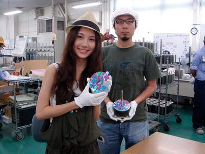 サインを施したCDを手にほほえむMayと、白い帽子をしっかりかぶって身も心も工場員となったDaichi。