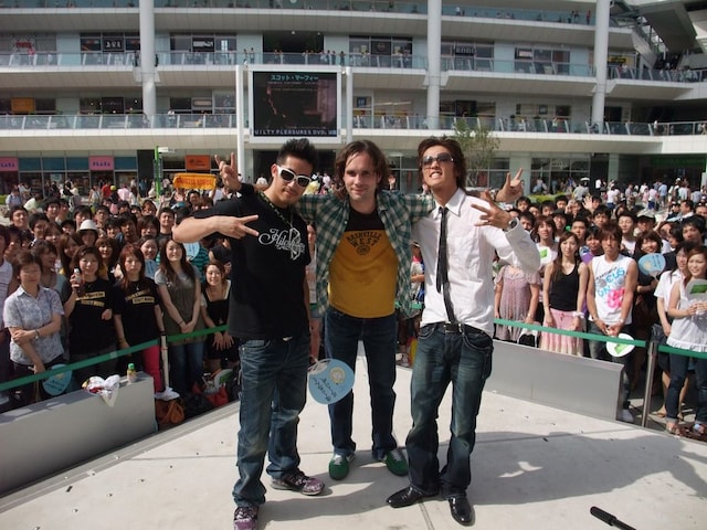 肩を組み、仲良しぶりをアピールするヒルクライムとスコット・マーフィー。2組は明日7月22日に東京・お台場合衆国オダイバ州フジテレビランド1F広場で開催されるライブイベントでも競演する。