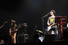 写真は7月9日の武道館ライブの模様。「12CAMS;QURULI@NIPPON BUDOKAN」は、現在WEB上で展開中の「謎の板×クエスト」など斬新な試みを続けるくるりからの新たなプレゼントとなりそうだ。