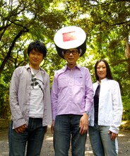 木恵つよし（G/写真左）、サエキけんぞう（Vo/中央）、NANASE（P/右）の3人からなるフレンチポップユニット、サエキけんぞう＆クラブ・ジュテーム。サエキが頭に乗せているスシはマグロ、海老に続く新作、鉄火巻きに変わっている。