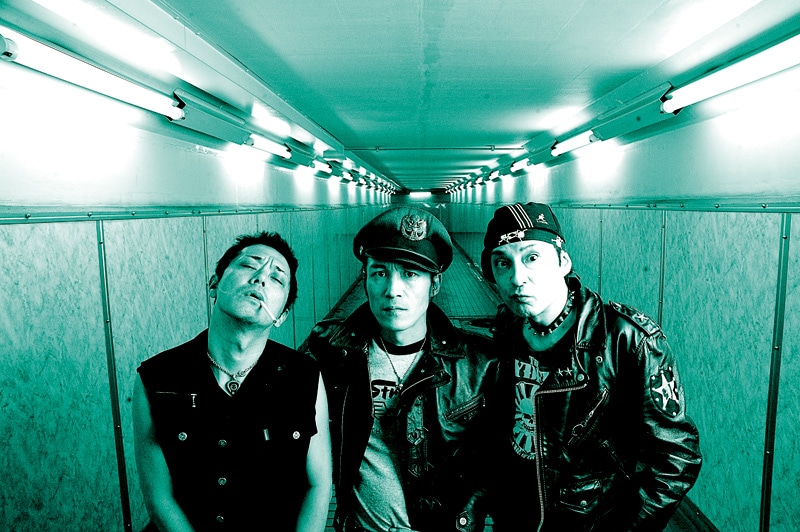 写真左からHIKAGE(THE STAR CLUB)、IWATA(The STRUMMERS)、OHNO(THE RYDERS)。80年代から日本のパンクシーンを牽引してきた3バンドが、新宿LOFTで「DOLL」への鎮魂歌(=パンクロック)を爆音で鳴らす。