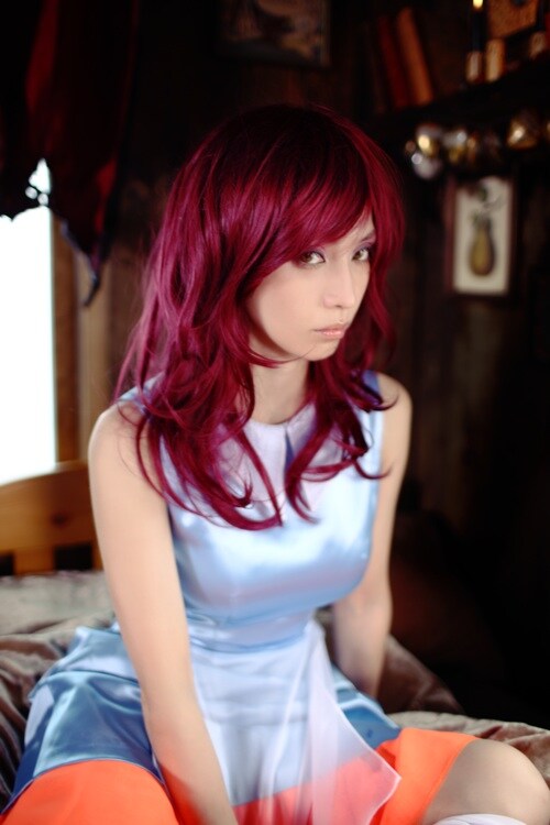 緋色の髪と個性的なデザインのワンピースで、童話の主人公のようなビジュアルに。