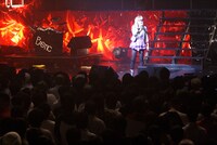 MC中のアイラはリラックスした様子。ステージセットはアルバム「PLASTIC」のジャケットを思わせる、赤と黒の2色に統一されている。