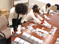 ジャケットと封入カードを並べ、次々と刻印していく4人。